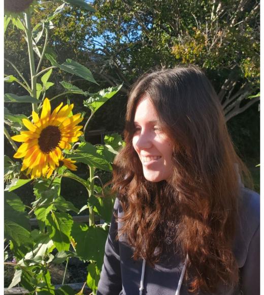Photo of Miranda, peer advisor outdoor with a sunflower